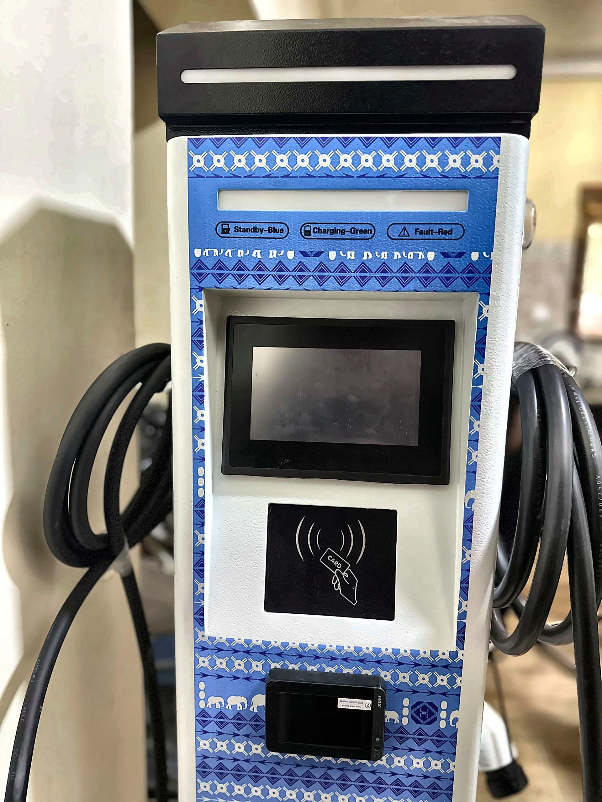 A freestanding EV charging station with a touchscreen, RFID card reader, and coiled charging cables